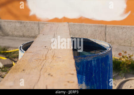 Albero di legno su blu di plastica riempito di acqua la canna nel sito in costruzione in Italia con i colori dei tubi di plastica sullo sfondo e rosso e bianco e a parete Foto Stock