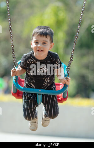 Ragazzo sorridente oscillanti in uno swing Foto Stock