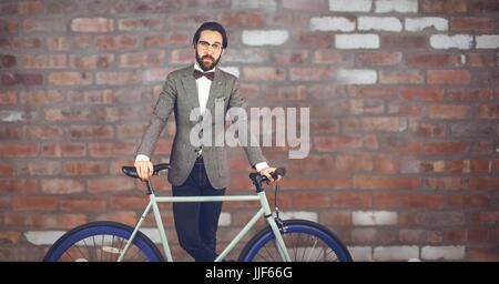 Composito Digitale di riflettere hipster uomo con una bicicletta di fronte red muro di pietra Foto Stock