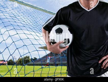 Composito Digitale del giocatore di calcio con la palla sul suo braccio nella parte anteriore dell'obiettivo Foto Stock