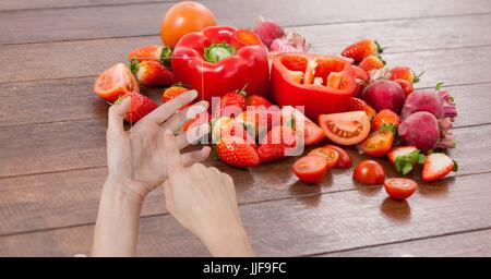 Composito Digitale di mano tenendo l'immagine della frutta e della verdura attraverso il dispositivo Foto Stock