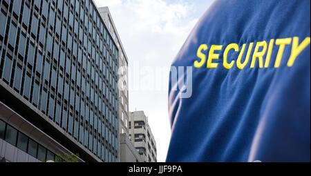 Composito Digitale della persona di sicurezza con giacca blu nella parte anteriore di un grande edificio Foto Stock