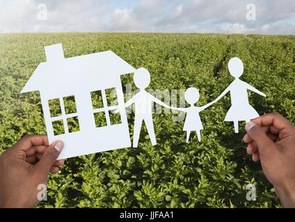 Digital composito di ritagli Casa e famiglia nelle mani oltre il paesaggio Foto Stock