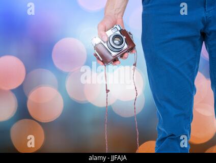 Composito Digitale della mano che tiene la fotocamera con luce sfavillante sfondo bokeh di fondo Foto Stock