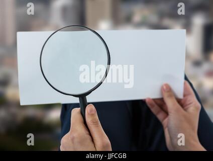 Digital composito di lente di ingrandimento nella mani guardando la carta sulla città Foto Stock