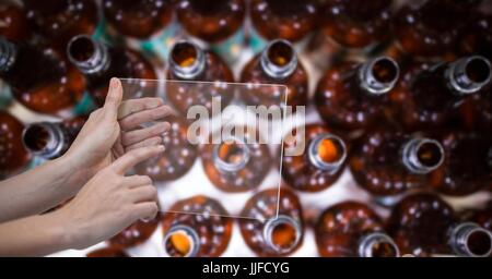 Digital composito di direttamente sopra il colpo di mano di scattare una foto di bottiglie di alcol attraverso il dispositivo trasparente alla birreria Foto Stock