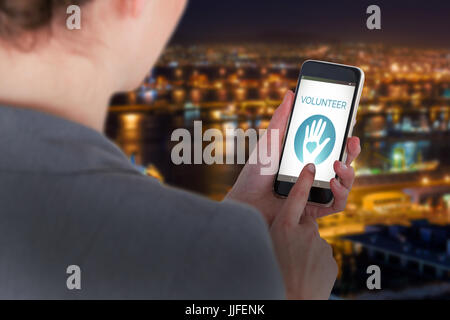 Close-up di imprenditrice utilizzando il telefono cellulare contro il porto illuminato contro il paesaggio urbano Foto Stock