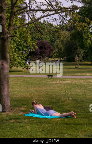 Una donna a prendere il sole e godersi l'estate a Regent's Park, London, Regno Unito Foto Stock