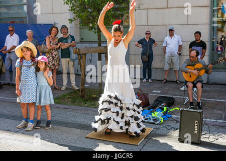 Il chitarrista e la ballerina di flamenco con il tradizionale abito bianco a ballare come street performance durante le feste estive Foto Stock