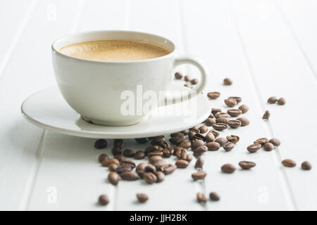 Caffè caldo cappuccino e caffè in grani sul tavolo bianco. Foto Stock