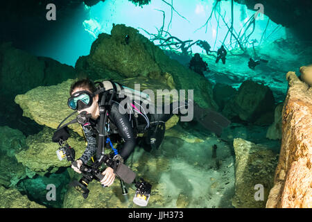 Un subacqueo nuota all' ingresso del Car Wash cenote nella penisola dello Yucatan in Messico. Foto Stock