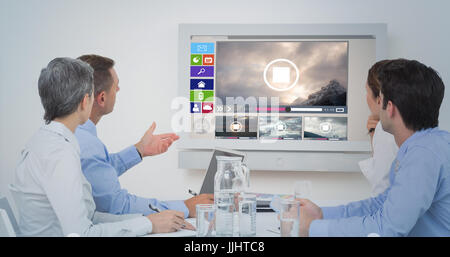 Attento team aziendale durante una conferenza contro generati digitalmente immagine di vari video e icone visualizzate Foto Stock