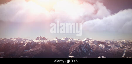 In modo digitale immagine composita del cloud contro montagne coperte di neve contro il cielo chiaro Foto Stock