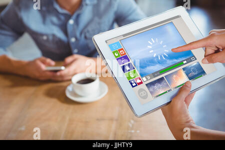 Immagine composita di vari video e icone del computer contro la persona che usa il computer tablet in cafe Foto Stock