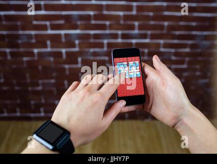 Mani con telefono davanti a un muro di mattoni. Nel telefono la progettazione di un nuovo muro. Foto Stock
