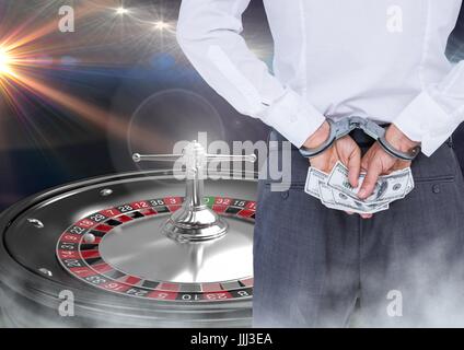 Uomo in mano i bracciali con denaro e 3d macchina roulette Foto Stock