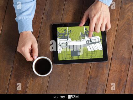Tablet con mani e caffè su una scrivania. Sulla tavoletta, verde e grigio cianografia Foto Stock