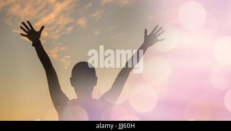 Vista posteriore di sportivo da uomo con braccia alzate con bokeh di fondo contro sky Foto Stock
