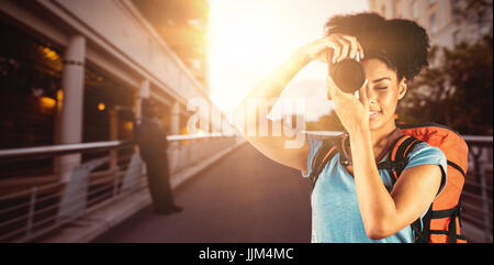 Immagine composita della giovane donna con zaino di scattare una foto Foto Stock