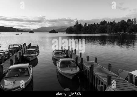 Tranquilla scena Crepuscolo di barche ormeggiate nei pontili nel lago di Windermere in Cumbria - foto in bianco e nero Foto Stock