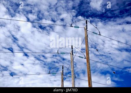 In prossimità dei poli di potenza e trasformatori di vetro contro il blu e il cielo bianco Foto Stock