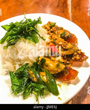 Frittura di mille anni di uovo con croccante di santo le foglie di basilico e il piatto di riso su una tavola di legno, piccante popolare tailandese tradizionale firma autentica menu per l Foto Stock