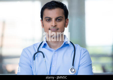 Closeup ritratto di cordiale e sorridente fiducioso medico maschio, professionisti sanitari con uno stetoscopio attorno al collo, braccia incrociate. Foto Stock