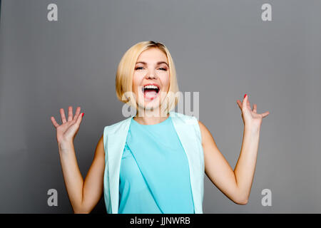 Bella donna con le mani alzate sul vuoto sfondo bianco Foto Stock