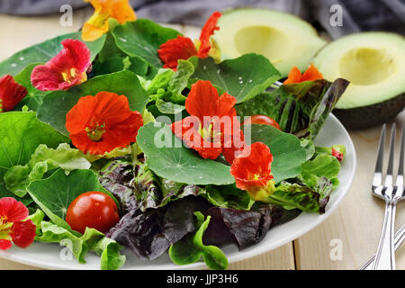 Insalata fresca con fiori i Nasturzi, pomodorini e avocado. Messa a fuoco selettiva con estrema profondità di campo. Foto Stock