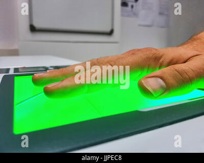 Vista laterale da un uomo utilizzando uno scanner di impronte digitali per l'identificazione. La biometria o i concetti di sicurezza informatica. Foto Stock