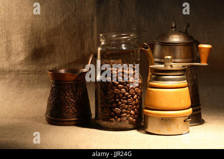 Il caffè turco.il vasetto di vetro con i chicchi di caffè nei pressi della vecchia caffettiera in rame su tela lo sfondo Foto Stock