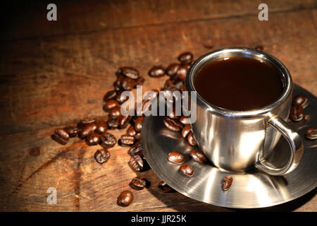 Acciaio tazza di caffè e fagioli su una superficie di legno Foto Stock