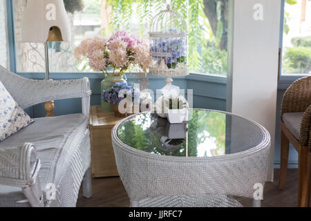 Accogliente blue rattan divano con cuscino in cotone in salotto accanto alla finestra con vista sul giardino in casa moderna. home interior design Foto Stock