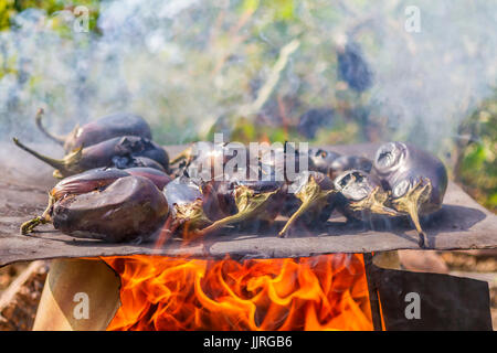 Le melanzane cottura su una piastra di metallo su un fuoco aperto. Le melanzane cottura sull'arrosto naturale cibo. Foto Stock