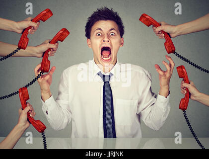 Uomo d'affari ha sottolineato e nervoso da a molte chiamate di lavoro urlando in disperazione nel suo ufficio Foto Stock