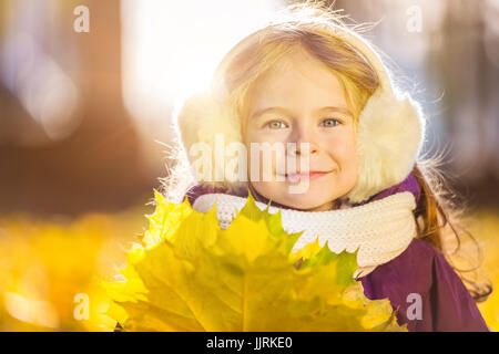 Felice bambina earflaps con foglie di autunno Foto Stock