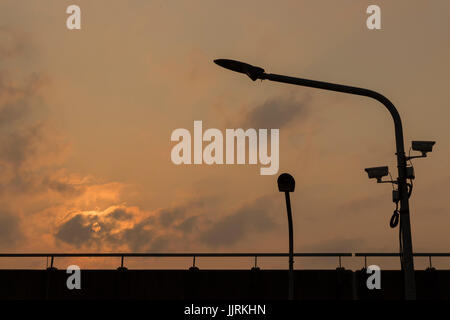 Silhouette luce LED poli e cctv sulla superstrada con orange sfondo con cielo nuvoloso ;Bangkok in Thailandia. Foto Stock