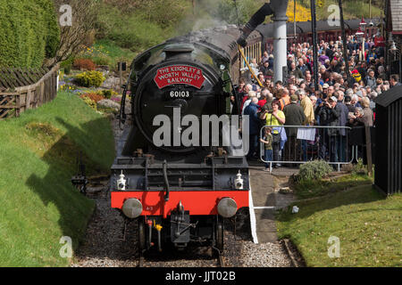 Una folla di persone di visualizzare iconico locomotiva a vapore 60103 Flying Scotsman, sbuffando fumo sulle vie - Keighley e Worth Valley Railway Station, Inghilterra, Regno Unito. Foto Stock