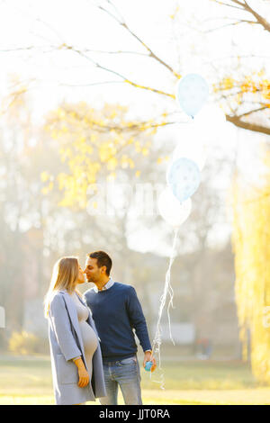 Coppia giovane aspettano di baby e divertirsi con palloncini in autunno park Foto Stock