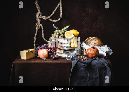 Un classico still-life in stile olandese con formaggio frutta e libri su un colore marrone scuro dello sfondo. con tendaggi Foto Stock