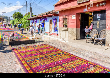 Antigua Guatemala - marzo 26, 2017: la gente fa segatura colorata processione tappeti durante la quaresima contro il fondale di agua vulcano in città coloniale Foto Stock