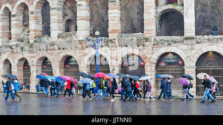 VERONA Italia un giorno di pioggia all'arena per i turisti con ombrelloni colorati Foto Stock