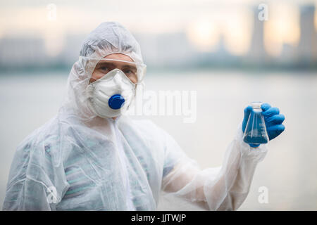 Ecologista nel respiratore con provetta su sfondo sfocato Foto Stock