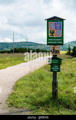 Il cartello in legno informa di Giant Mountains National Park (Krkonose). Su uno sfondo è il sentiero che conduce a Zlate navrsi, lontani di montagna, alberi e Foto Stock