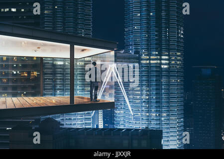 Imprenditore in un moderno ufficio del cielo di notte con splendida vista dello skyline della citta' . Foto Stock