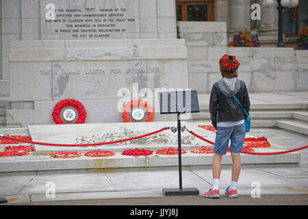 Giovane ragazzo adolescente in tartan Tammy davanti al memoriale di guerra il cenotafio George Square Glasgow papaveri rossi Foto Stock
