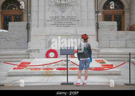 Giovane ragazzo adolescente in tartan Tammy davanti al memoriale di guerra il cenotafio George Square Glasgow papaveri rossi Foto Stock