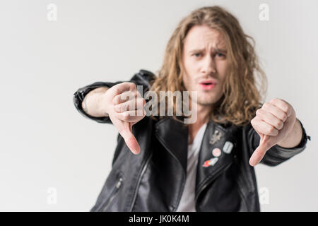 Giovane uomo bello in nero giacca di pelle che mostra il pollice verso il basso isolato su grigio Foto Stock