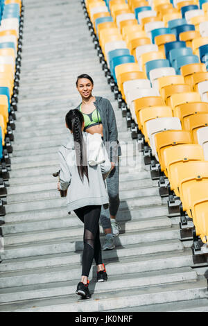 Sorridente giovani donne fitness in sportswear camminando tra sedi stadium Foto Stock