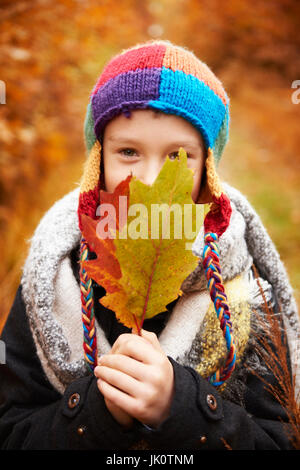 Ragazzo che ricopre la faccia con foglie di autunno Foto Stock